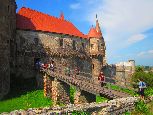 Monumentalny średniowieczny zamek w Huneodarze. Mimo, że sprawia wrażenie potężnej fortecy, pełnił on zawsze rolę szlacheckiej rezydencji. Pierwotna warownia powstałą tu już prawdopodobnie na przełomie XII i XIII wieku. W XIV wieku twierdza przeszła w ręce panujących wtedy na terenie obecnych Węgier i Rumunii - wywodzących się z zachodniej Francji - Andegawenów. W pierwszej połowie XV wieku zamek odziedziczył późniejszy regent Węgier i władca Transylwanii - Jan Hunyady. To właśnie z jego inicjatywy nastąpiła pierwsza większa rozbudowa warowni. Powstały wtedy m in. dwa pierścienie murów obronnych, zamek właściwy oraz kaplica. Kolejne prace budowlane prowadzone były przez syna Hunyadyego - króla Węgier - Macieja Korwina (1443-1490). W kolejnych wiekach warownia wielokrotnie zmieniała swoich właścicieli. Jednym z ważniejszych był książę Siedmiogrodu i przywódca powstania antyhabsburskiego - Gábor Bethlen. Za jego rządów powstała m in. Biała Wieża, Wieża Bramowa oraz taras artyleryjski. Za panowania Habsburgów w zamku urządzono skład materiałów co spowodowało jego dewastację. W 1854 roku szalejący pożar zniszczył konstrukcję drewnianych stropów, co spowodowało zawalenie się dachu. Pierwsze prace konserwatorskie przeprowadzono tu dopiero na przełomie XIX i XX wieku. Gruntowna odbudowa przywracająca twierdzy jej dawną świetność przeprowadzona została dopiero w latach pięćdziesiątych XX wieku. Dziś najcenniejszym elementem warowni jest majestatyczna gotycka Sala Rycerska z krzyżowo-żebrowym sklepieniem wspartym granitowymi filarami. Bezpośrednio nad nią znajduje się Sala Rady w której Gábor Bethlen zwoływał sesje siedmiogrodzkiego parlamentu. Obecnie w pełni odrestaurowany Zamek w Hunedoarze zaliczany jest do najpopularniejszych atrakcji turystycznych Rumunii. Każdego roku przyjeżdżają tu tysiące turystów